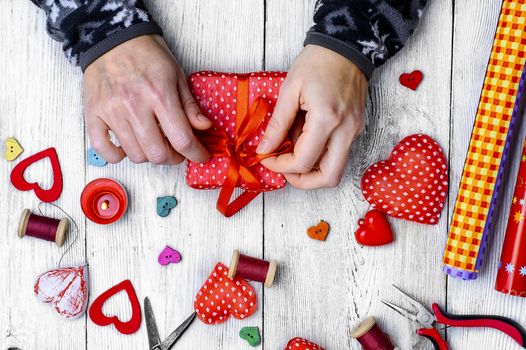 Packing holiday gifts for Valentine's day.Thread,button and symbolic heart.