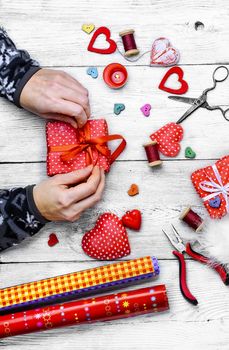 Packing holiday gifts for Valentine's day.Thread,button and symbolic heart.