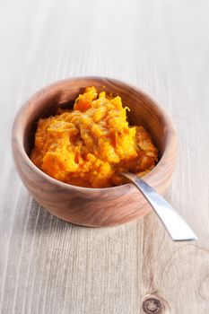 Pumpkin puree with a spoon on a wooden surface.