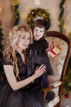 Mother and daughter with gift-box under Christmas tree