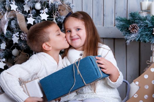 Sweet boy kissing girl under Christmas tree