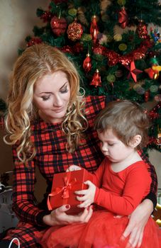 Mother and baby girl under Christmas tree with red gift-box