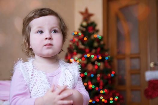 Cute baby girl over lit Christmas tree