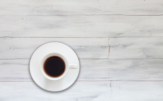 Top view of cup of fresh espresso on white wooden background