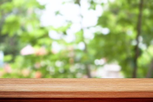 Wood table top on bokeh green leaves background, for display your products