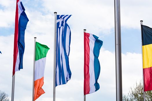 Several Europe countries flags arranged in front of a blue sky.