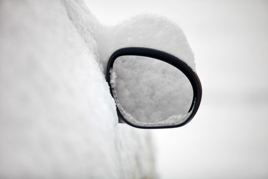 Car rearview mirror under snow in winter