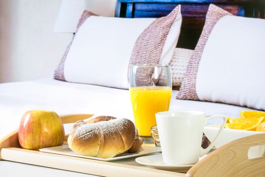 Tray with a continental breakfast on a bed in a hotel room.