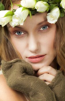 A portrait of beautiful young woman with colorful eyes and white roses wreath.