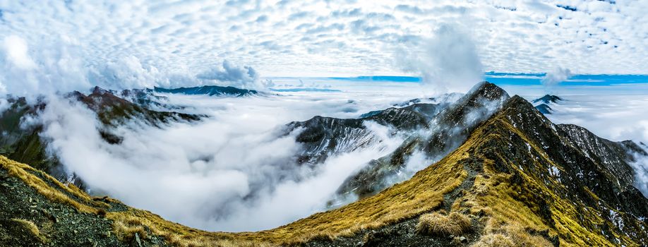 Panorama mountain ranges above the clouds. Autumn in the Romanian Carpathians