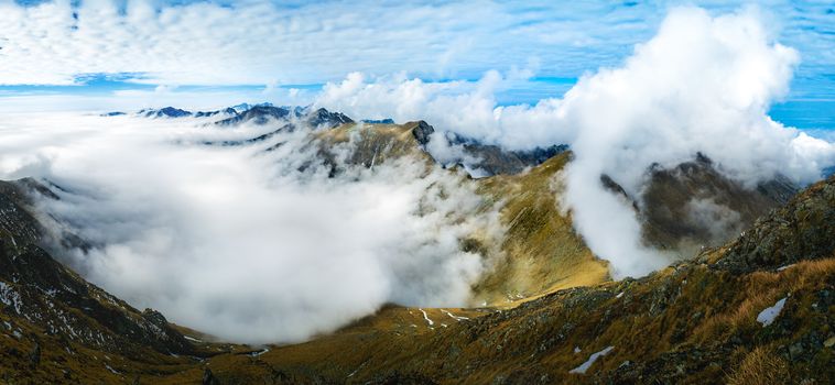 View of the mountain range above the mist. Fluffy clouds on tops. Autumn in the Romanian Carpathians