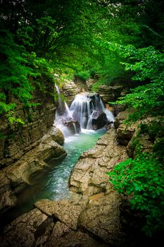 Waterfall in a canyon. Forest around the river. Clear water. Georgia. Vignetting effect.