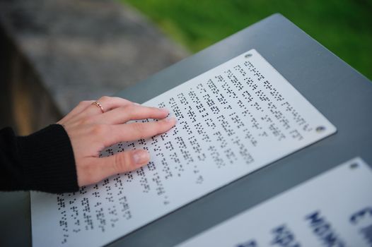 text for the blind on metal plate in park.