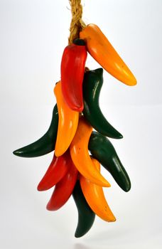 Assortment of red, green and yellow peppers on a rope in white background