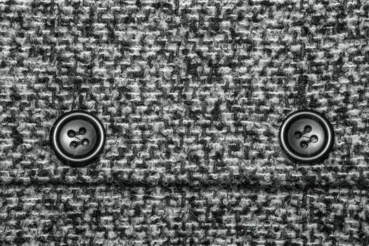 Varicolored tweed like texture, varicolored wool pattern, textured melange upholstery fabric background copy space. Background texture of twill with two big black buttons