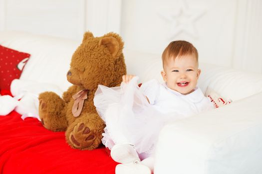 beautiful baby girl laughing and having fun sitting on the couch in the interior with Christmas decorations.