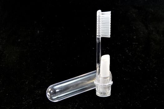 Transparent plastic toothbrush for travel on a black background