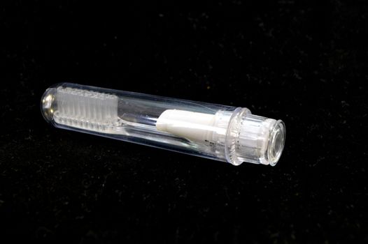 Transparent plastic toothbrush for travel on a black background