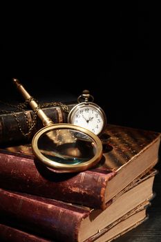 Vintage still life. Magnifying glass and pocket watch on old books