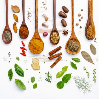 Various herbs and spices in wooden spoons. Flat lay of spices ingredients chilli ,pepper, garlic,dries thyme, cinnamon,star anise, nutmeg,rosemary, sweet basil and kaffir lime on wooden background.