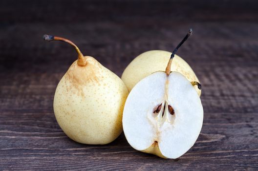 Pears, whole and half rests on a wooden surface. Selective focus, low key.