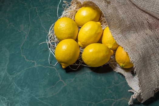 Fresh picked lemons spilling from a burlap sack. Horizontal format with copy space.