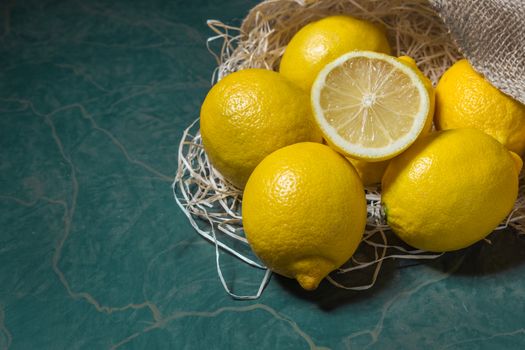 Fresh picked lemons spilling from a burlap sack close up. Horizontal format with copy space.