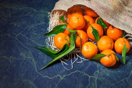 Fresh picked mandarins spilling from a burlap sack. Horizontal format with copy space.