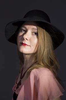 Portrait of a young woman in a hat on a black background