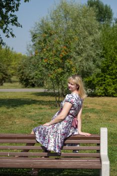 Pregnant woman sitting on wooden bench in park