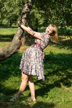 Pregnant woman clinging to a tree trunk in the Park Sunny summer day