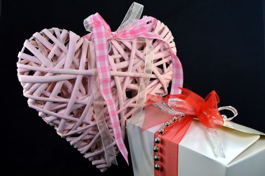 Box of pralines and a pink heart with a ribbon on a black background