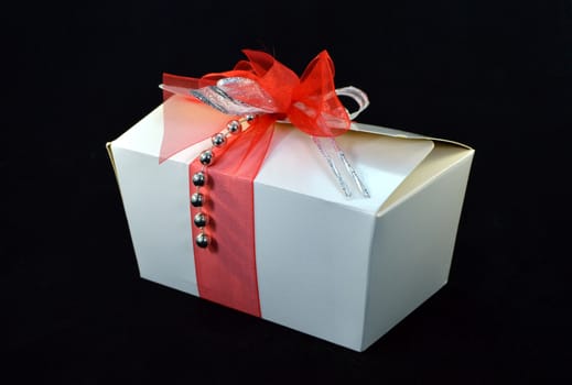 Box of white pralines with a bow on a black background