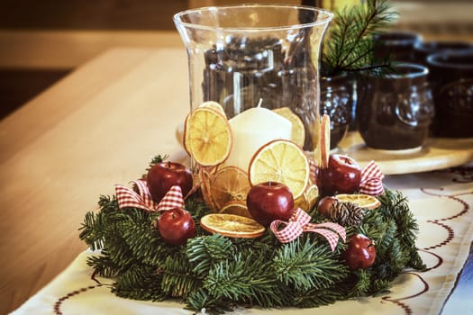 Candle in a glass vase and Christmas decoration on a wooden table