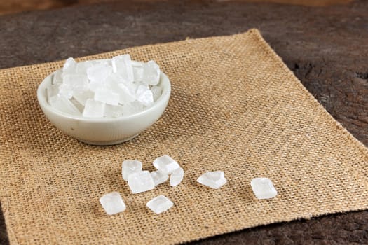 rock sugar in a cup decorated with sack on old wood. 