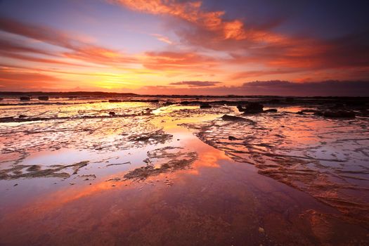 Sunrise skies reflecting on the exposed rock shelf at Long Reef, Northern Beaches, Australia