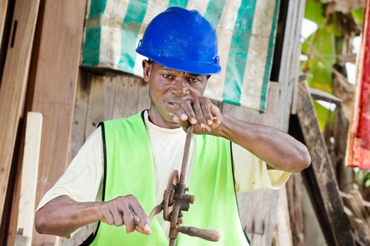 The carpenter in his workshop made with wood, is now turning a crank.