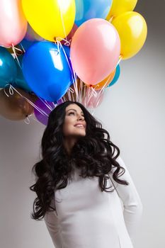 Cheerful woman holding many colorful balloons, celebration and happiness concept