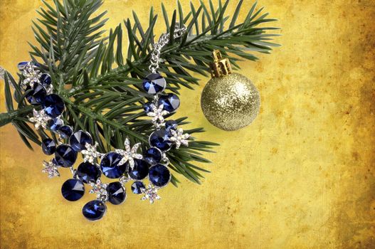 necklace with blue stones on a branch of a Christmas tree with a  ball on an abstract background