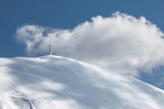 The cross of Mount Catria and clouds against a blue sky