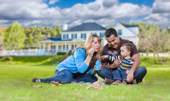 Happy Mixed Race Ethnic Family Playing with Bubbles In Their Front Yard.