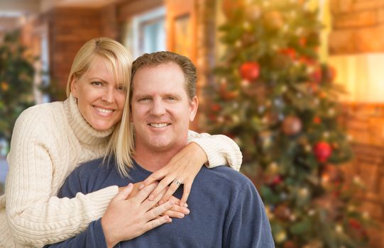 Happy Loving Caucasian Couple Portrait In Front of Christmas Tree Indoors.