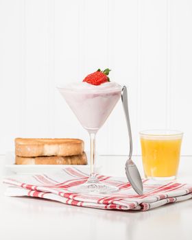 Glass filled with greek yogurt garnished with a ripe strawberry.