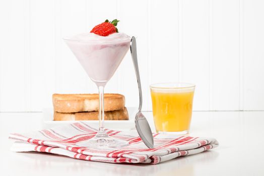Strawberry greek yogurt served with toast and orange juice.