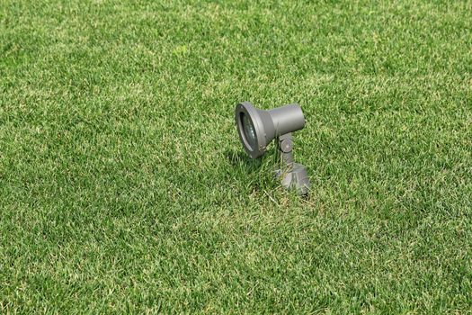 Metal solar-powered garden lamp on a background of green grass.