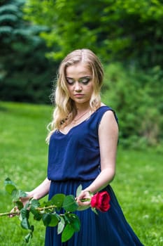 beautiful girl holding a red rose in the Park