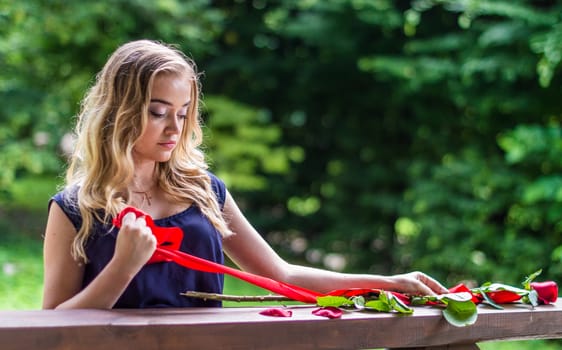 beautiful girl with rose and red tape in the park