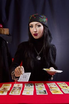 Gypsy woman wonders on the Tarot cards on a black background