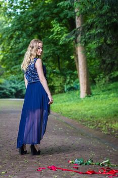 beautiful girl drags rose on the ground in the park