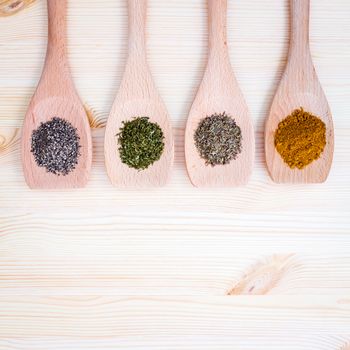 Food cooking ingredients dried spices herb in wooden spoon curry powder ,black pepper,dried thyme and dried sweet basil on wooden background.